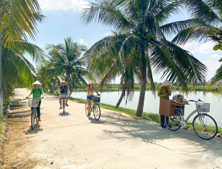 Cycling a palm-lined lane beside the river - Rose Travel